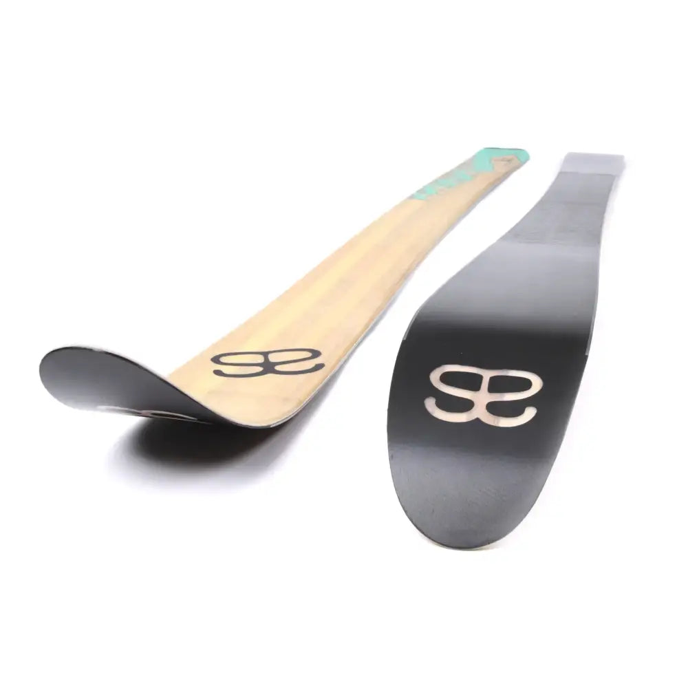 Two altai kom 174cm ski boards with natural wood finish and matte black surface featuring embossed logo