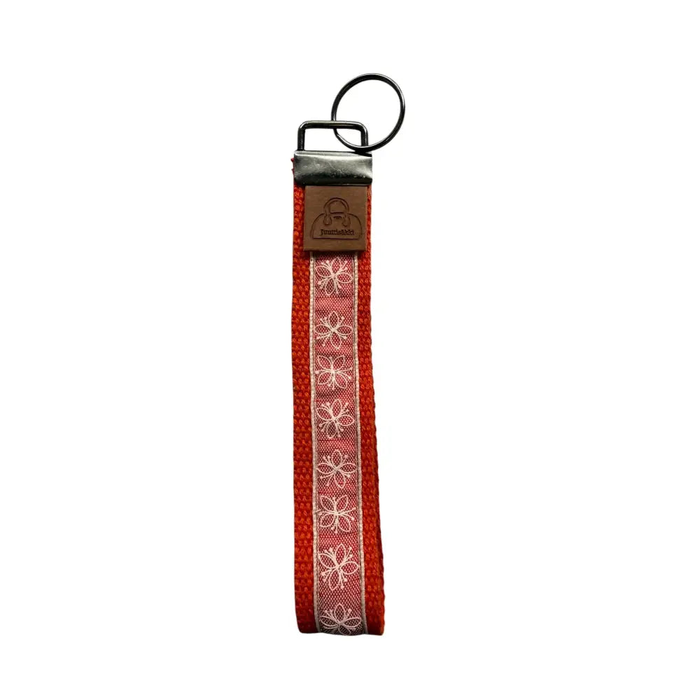 Avaimenperä lenkki red woven keychain with white floral embroidery and brown leather tag