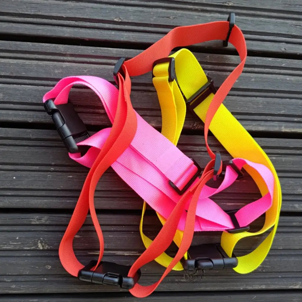 Neonpinkkejä, oransseja ja keltaisia nailonista valmistettuja extension waistbelt- ja safety strap -turvavaljaita mustilla muovisoljilla