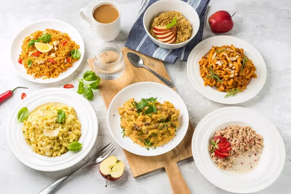Tässä ruokapakkauksessa food force viikon ruokapakkaus on värikkäitä tuoreita pastaruokia valkoisilla lautasilla
