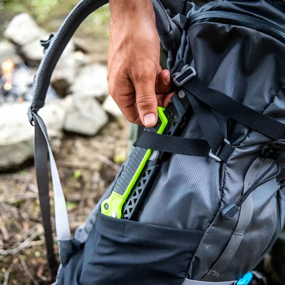 Gerber Freescape camp saw bright green and black multi tool with textured grip in the side pocket of a dark gray backpack
