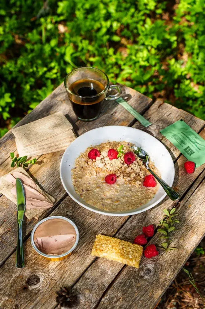 A white ceramic bowl of granola muesli with fresh red raspberries and green herbs for breakfast food force aamiainen