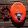 Kirkas oranssi 360swim h2o swim buoy -uintipussi sisäänrakennetulla vesipullotelineellä ja punaisella säädettävällä hihnalla