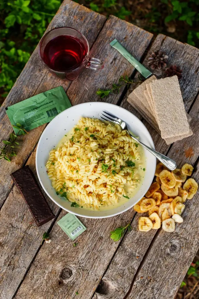 Kana-pasta retkiateria valkoisessa keraamisessa kulhossa kierteistä pastaa kermaisessa kastikkeessa ja yrttejä