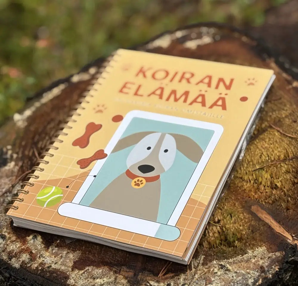 Keltainen spiraalilla sidottu koiran elämää -haavakirja, jossa koiran piirros kannessa ja punainen otsikko