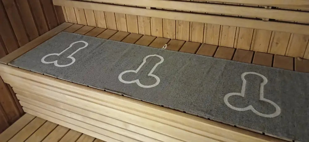 Gray textured sauna mat Laudeliina Kalunen with white outlined phallic symbols for sauna use