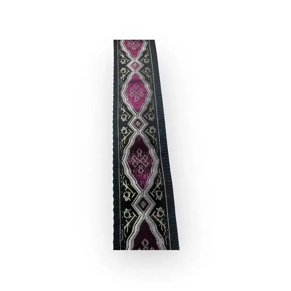 Laukun olkahihna mustalla kankaalla jossa on monimutkainen pinkki ja hopea geometrinen kuviointi