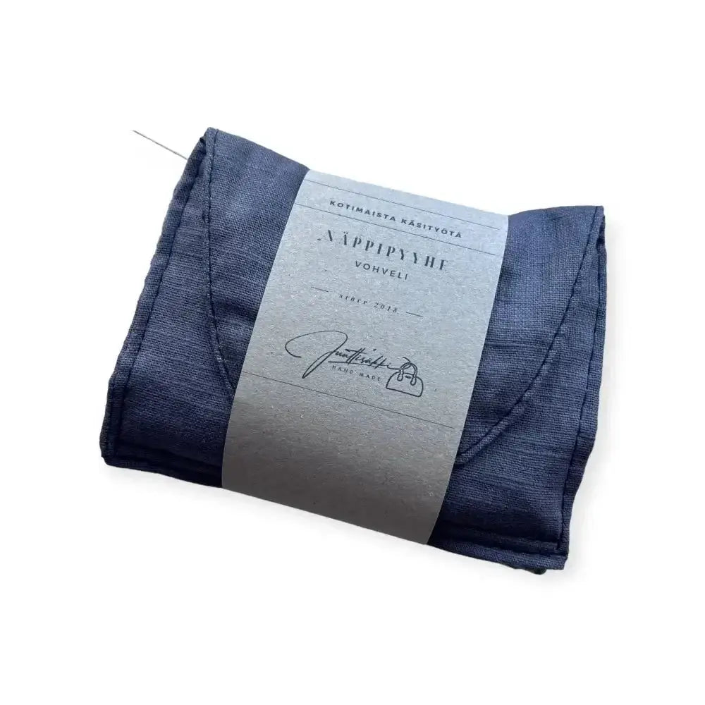 Dark blue linen napkin holder näppipyyhe with a silver label featuring finnish text and signature