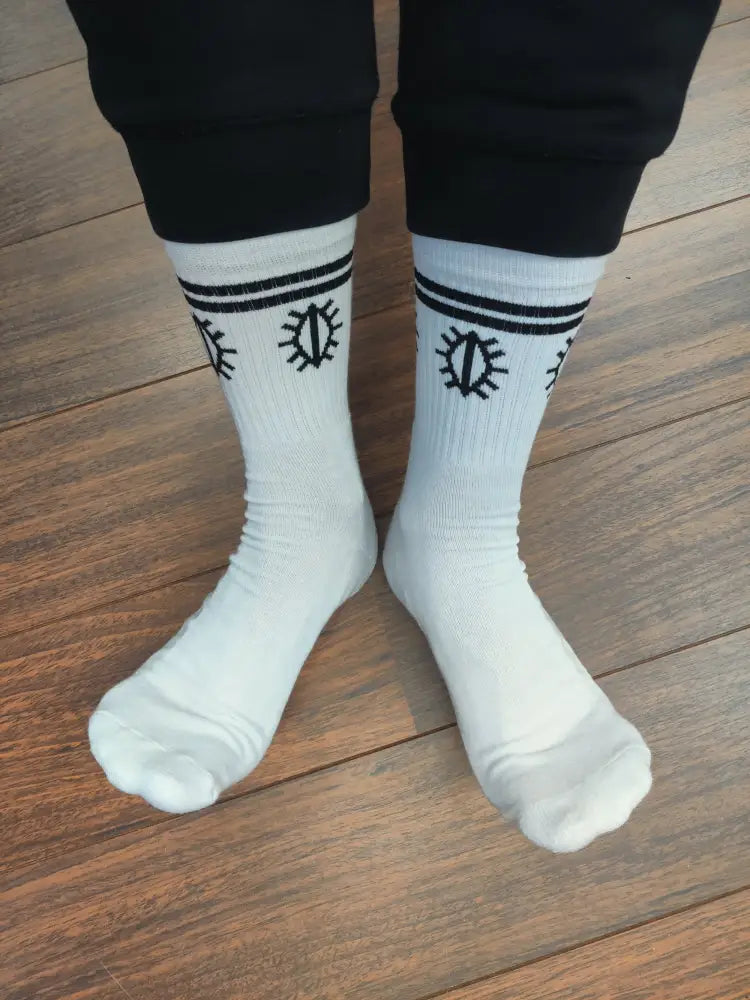 Valkoiset tennispimpsukat crew-sukat mustilla vaakaraitoja ja auringon sädekuviolla yläosassa