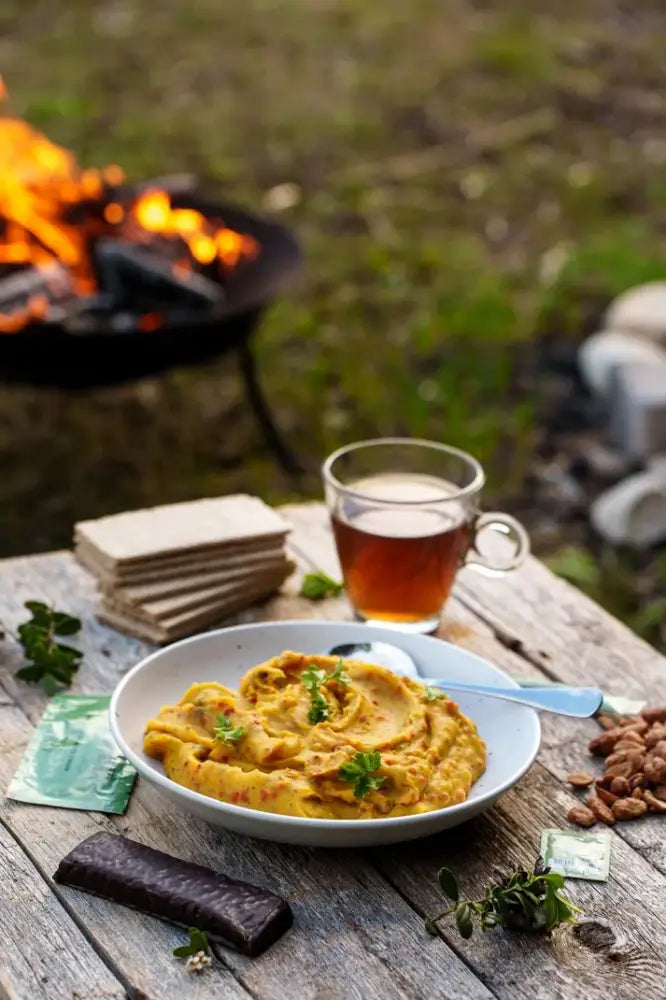 Kermainen oranssi hummus valkoisessa kulhossa, koristeltuna tuoreilla vihreillä yrteillä, potato stew with beef ateria