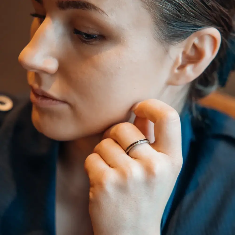 Puinen titaanisormus luoto kahden sävyn hopeanvärisenä minimalistisella designilla modelin sormessa