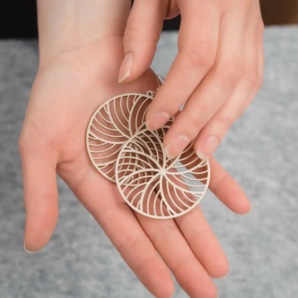 Delicate off-white puiset korvakorut with an intricate leaf-inspired cutout pattern