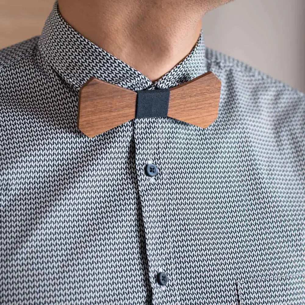 A sleek light brown wooden bow tie with a dark gray fabric center from puurusetti pähkinäpuu sininen collection
