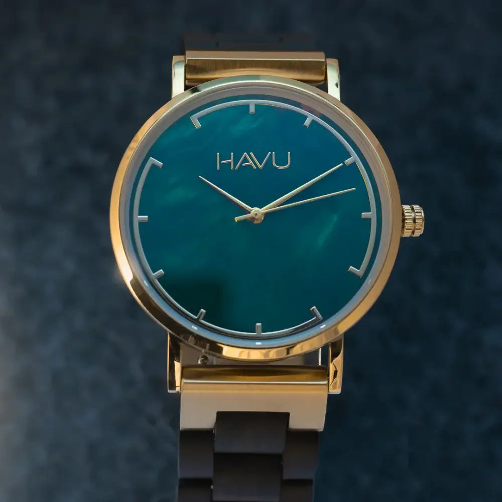 A sleek havu watch revontuli eebenpuu 40mm in vibrant teal dial with gold-tone hands and dark brown metal link bracelet
