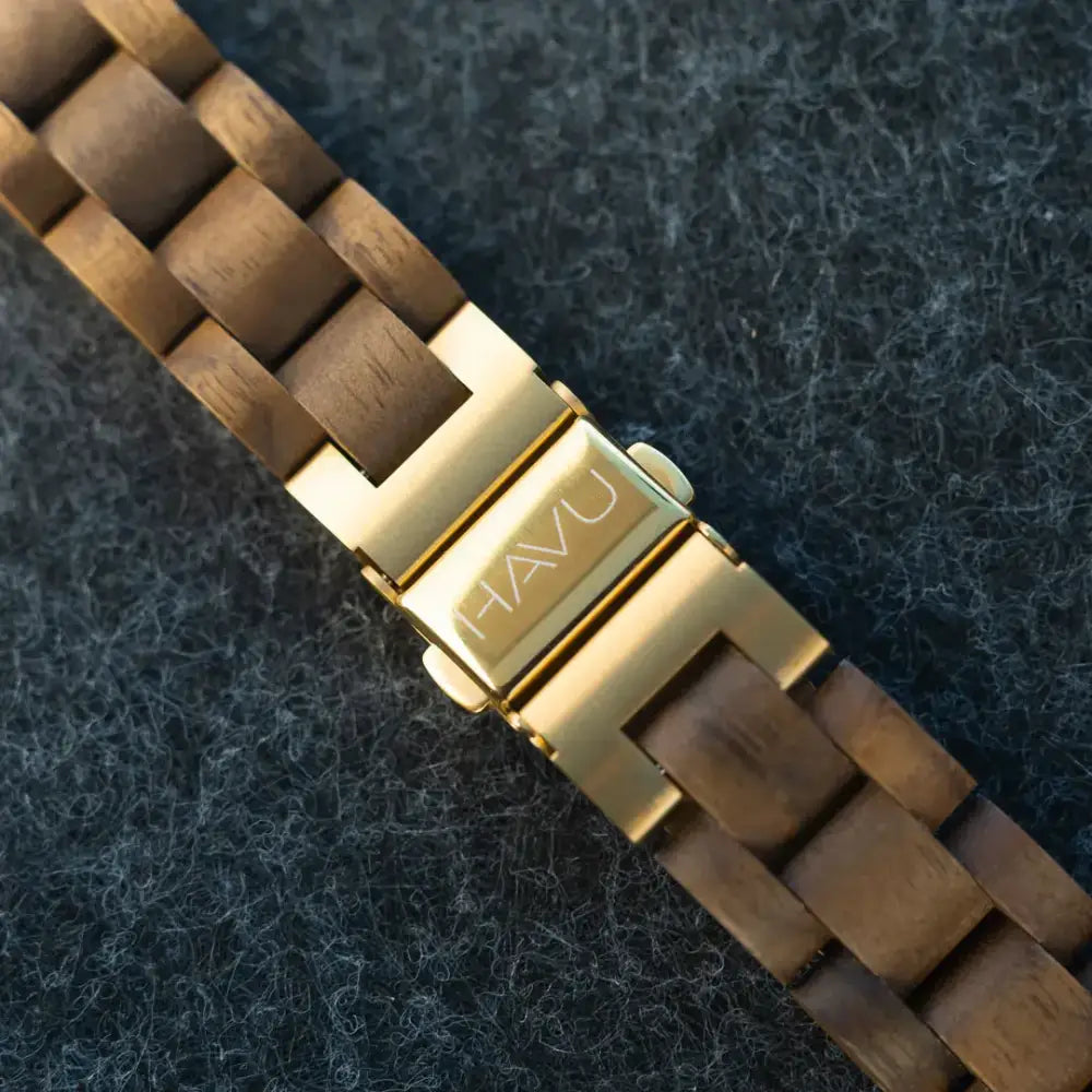 Goldtone metallinen solki jossa kuvioitu havu merkki puukellon rannekkeessa luonnollisella puunsyylle ja lämpimillä ruskeilla sävyillä revontuli pähkinäpuu 32mm ennakkomyynti