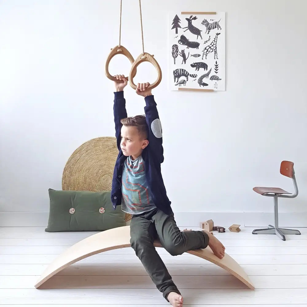 Light-colored oak balance beam rings with smooth curved surface and natural wood grain finish in red