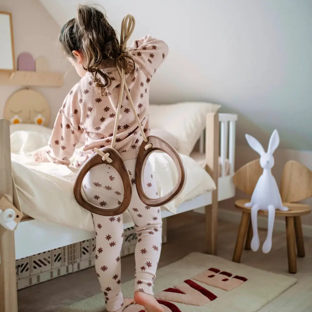 Lapsella leikillisesti selässään puinen kehys, jossa on pyöreät walnut-black -peilit ja beige köysihihnat