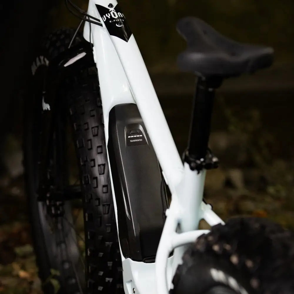White electric mountain bike rock machine vyöry e50r with black seat and shimano e-bike motor on down tube