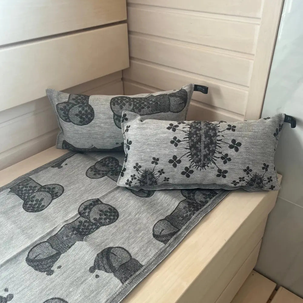Gray linen throw blanket with black embroidered phallic and clover patterns textured weave jokipiin pellava saunatyyny onnenkalu timber