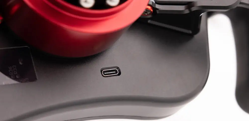 Musta usb-c-portti harmaalla mattapintaisella simagic fx-c formula ohjauspyörän takaosassa punaisen sylinterimäisen komponentin vieressä