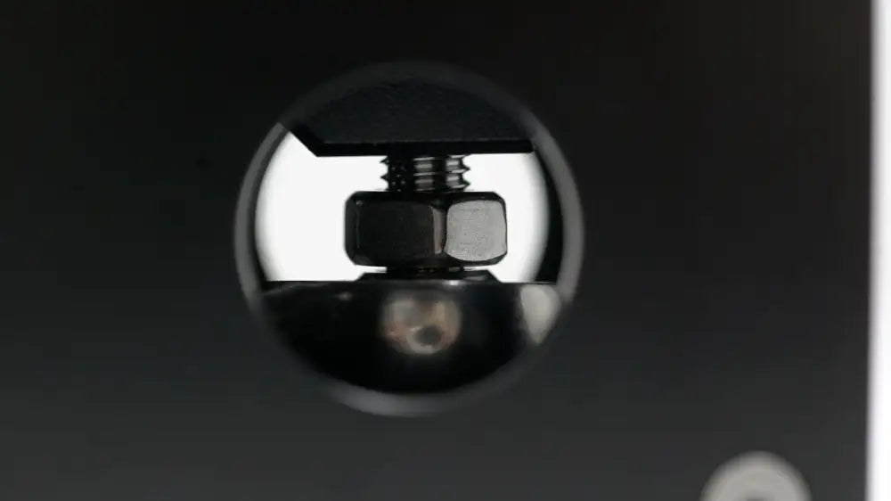 Black spherical camera lens cap with reflective surface showing hexagonal bolt and threaded screw under simagic q1 sequential shifter back side