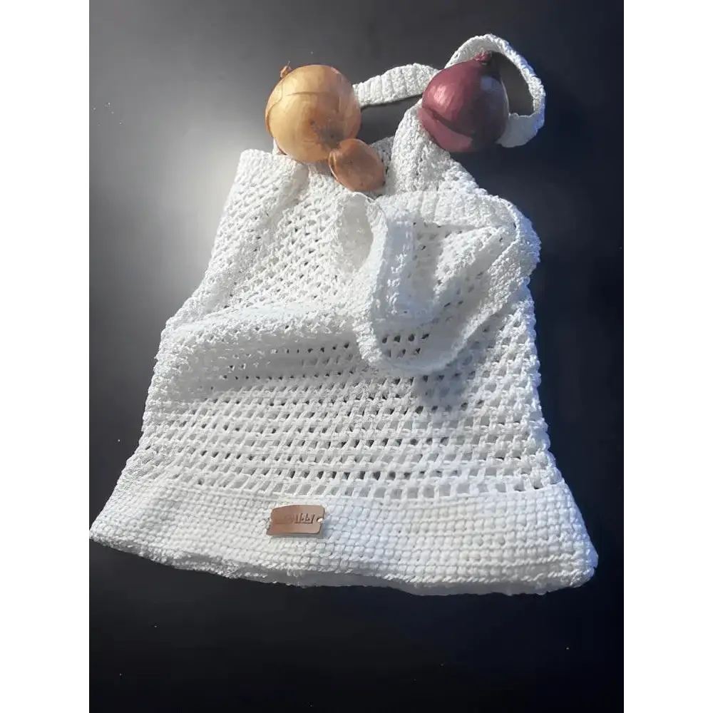 Valkoinen virkattu verkkokassi pienellä nahkaisella merkillä alareunassa