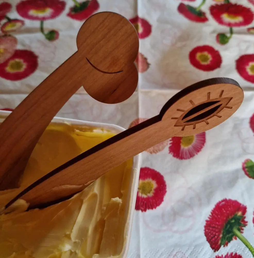 Wooden butter tongs voi vittu voiveitsi with carved smiley face and eye design in natural wood color